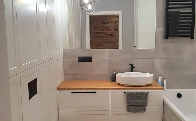 Nowoczesna łazienka z elementami industrialnymi i skandynawskimi, białe meble, drewniane akcenty.