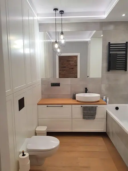Nowoczesna łazienka z elementami industrialnymi i skandynawskimi, białe meble, drewniane akcenty.