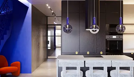 Wnętrze kuchni w stylu industrialnym, minimalistycznym i nowoczesnym z niebieską ścianą i czarnymi meblami.
