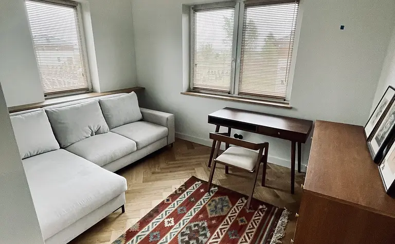 Wnętrze salonu w stylu eklektycznym z jasną sofą i dywanem vintage.