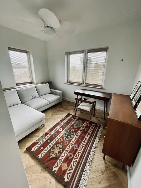 Wnętrze salonu w stylu eklektycznym z jasną sofą i dywanem vintage.