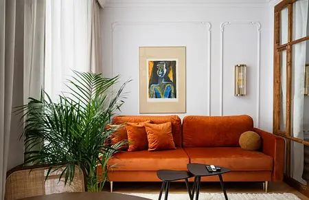 Wnętrze salonu z eklektycznym stylem, pomarańczowa sofa, roślina, nowoczesne akcenty.