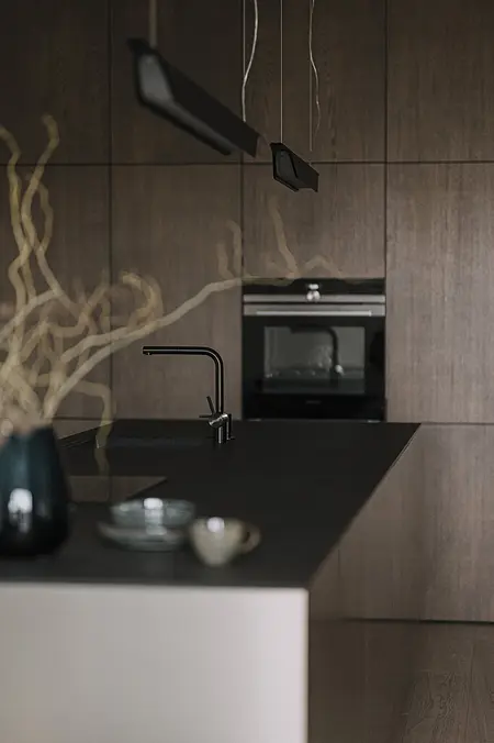 Kuchnia z ciemnymi meblami, blatem i akcesoriami w stylu minimaluxe, nowoczesnym i quiet luxury.