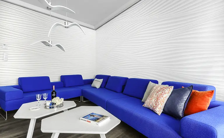 Nowoczesny salon w stylu skandynawskim z niebieską sofą i białą ścianą.