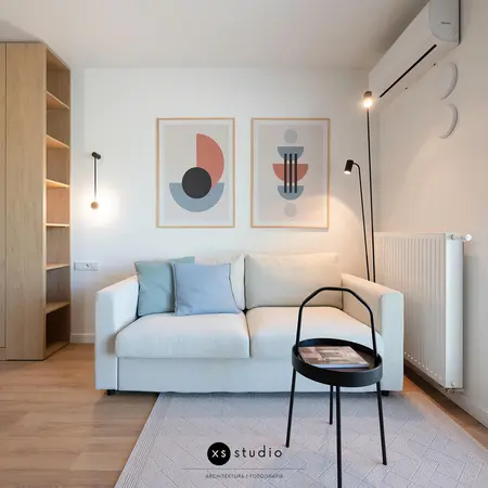 Wnętrze salonu w stylu skandynawskim z jasną sofą i drewnianymi detalami.
