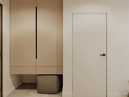 Minimalistyczny przedpokój z beżową szafą i nowoczesnymi drzwiami.
