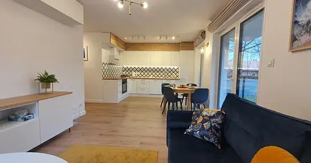 Wnętrze kuchni w stylu skandynawskim z białymi meblami i drewnianymi akcentami.