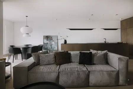 Wnętrze salonu z szarym narożnikiem, czarnymi akcentami i minimalistycznym wystrojem.