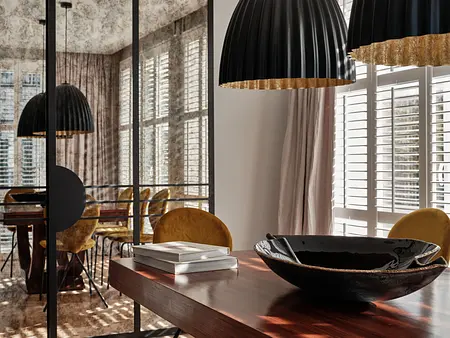 Wnętrze jadalni w stylu art deco i japandi z czarnymi lampami, drewnianym stołem i żółtymi krzesłami.