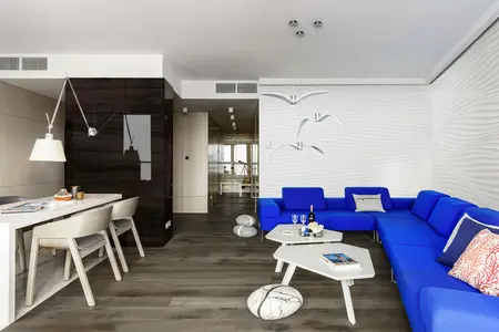 Wnętrze salonu w stylu skandynawskim z niebieską sofą i nowoczesnymi lampami.