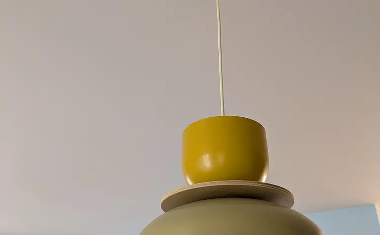 Lampa wisząca z zielonym i żółtym kloszem w nowoczesnym wnętrzu.