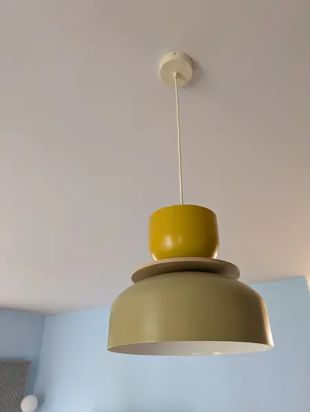 Lampa wisząca z zielonym i żółtym kloszem w nowoczesnym wnętrzu.