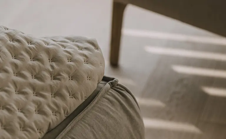 Wnętrze z beżowym fotelem i poduszką w stylu minimaluxe, nowoczesnym, quiet luxury, współczesnym.