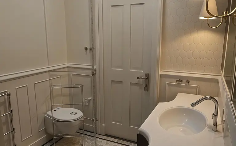 Wnętrze łazienki z płytkami hexagonalnymi, umywalką i toaletą, w stylu art deco i vintage.