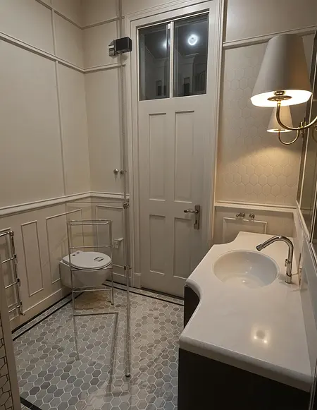 Wnętrze łazienki z płytkami hexagonalnymi, umywalką i toaletą, w stylu art deco i vintage.