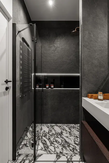 Współczesna łazienka z czarnymi ścianami i marmurową podłogą