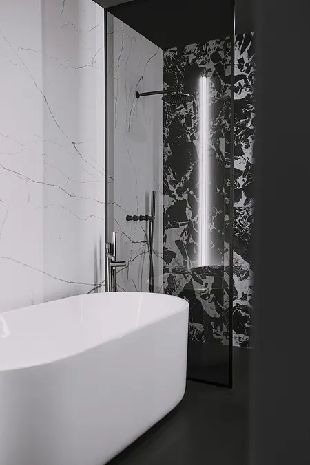 Nowoczesna łazienka z białą wanną i czarnym wykończeniem, minimalistyczny design.