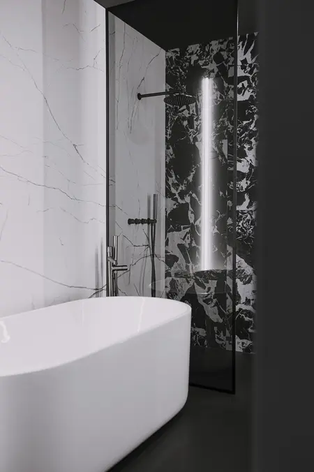 Nowoczesna łazienka z białą wanną i czarnym wykończeniem, minimalistyczny design.