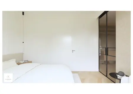 Minimalistyczna sypialnia z białymi ścianami i szafą przesuwną w stylu soft minimalizm.