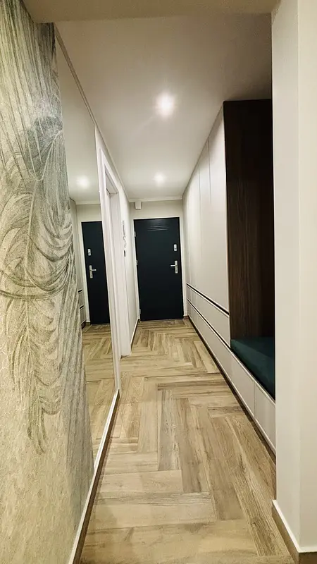 Przedpokój w stylu industrialnym i minimalistycznym z drewnianą podłogą i szafkami.