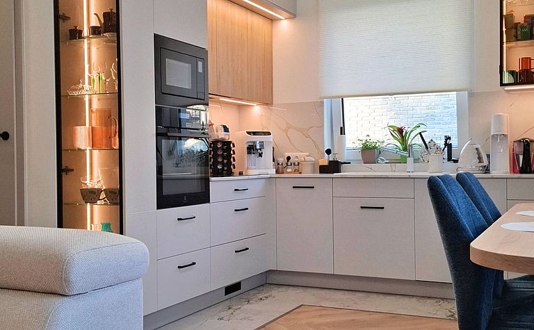 Kuchnia w stylu nowoczesnym i skandynawskim z jasnymi meblami i drewnianymi detalami.