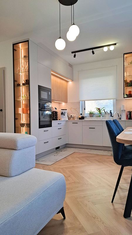 Kuchnia w stylu nowoczesnym i skandynawskim z jasnymi meblami i drewnianymi detalami.