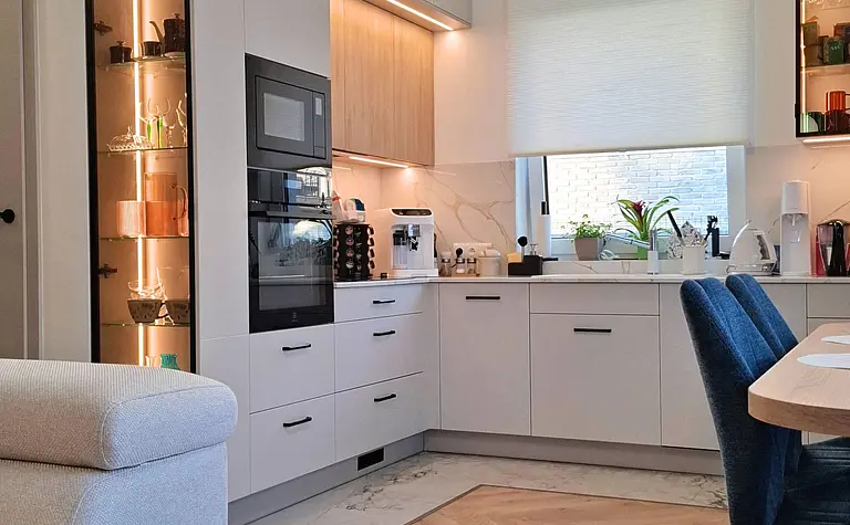 Kuchnia w stylu nowoczesnym i skandynawskim z jasnymi meblami i drewnianymi detalami.