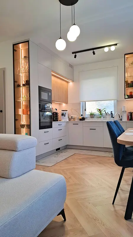 Kuchnia w stylu nowoczesnym i skandynawskim z jasnymi meblami i drewnianymi detalami.
