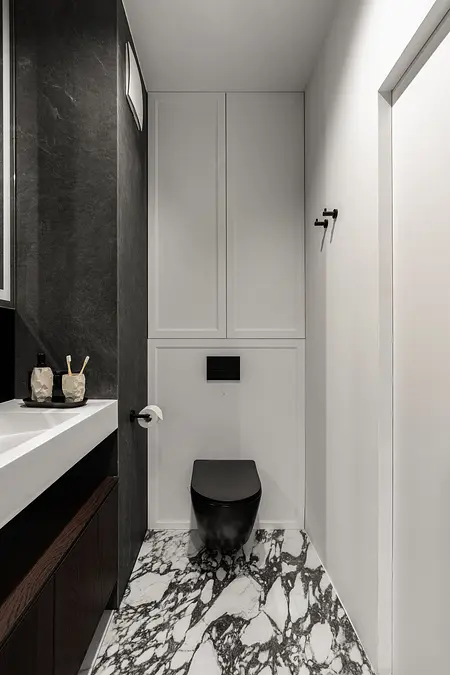 Nowoczesna toaleta z czarnymi i białymi elementami oraz marmurową podłogą.