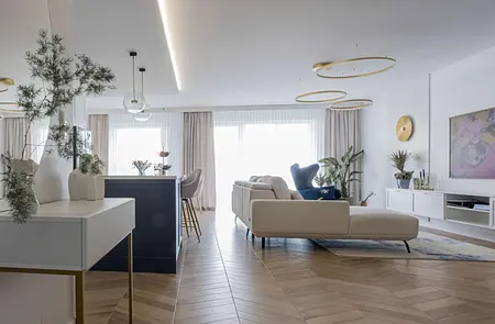 Wnętrze nowoczesnego salonu z jasnymi meblami i roślinami.
