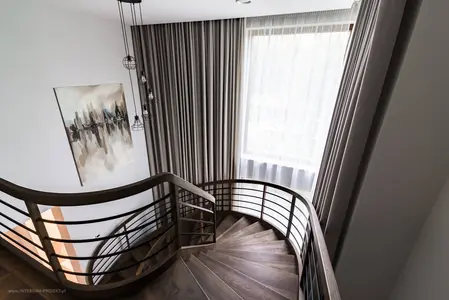 Klatka schodowa w stylu nowoczesnym z drewnianą balustradą, zasłonami i obrazem.