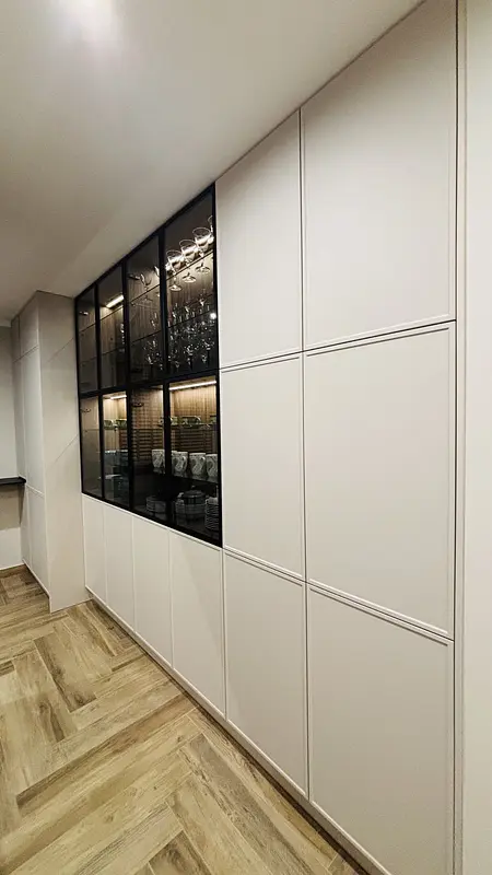 Wnętrze kuchni w stylu industrialnym z białymi meblami i drewnianą podłogą.