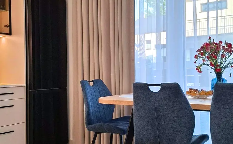 Jadalnia w stylu nowoczesnym i skandynawskim z drewnianym stołem oraz niebieskimi krzesłami.