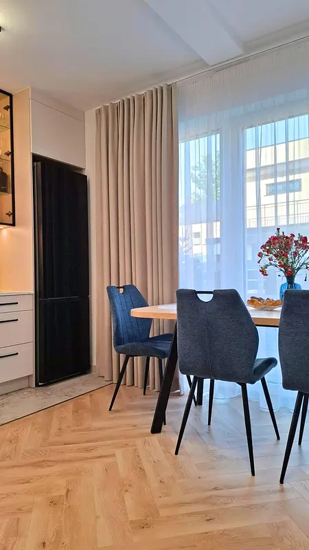 Jadalnia w stylu nowoczesnym i skandynawskim z drewnianym stołem oraz niebieskimi krzesłami.