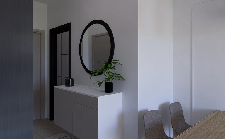 Przedpokój w stylu minimalistycznym z białą komodą i okrągłym lustrem.