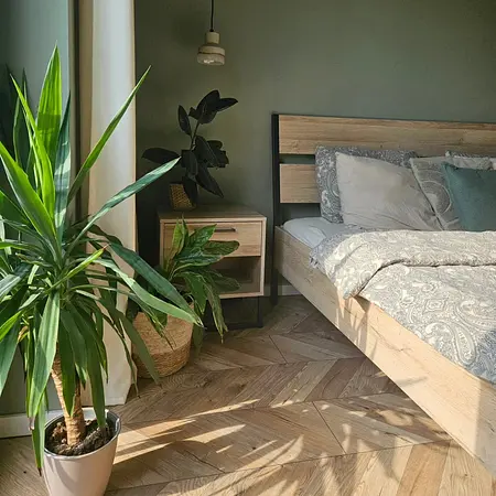 Wnętrze sypialni boho z drewnianym łóżkiem i roślinami.