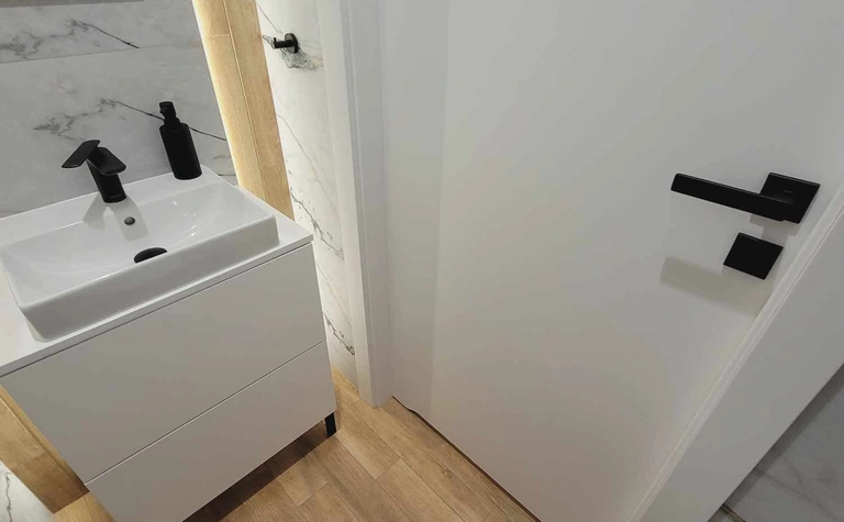 Minimalistyczna toaleta z białą umywalką i drewnianą podłogą, nowoczesne akcenty
