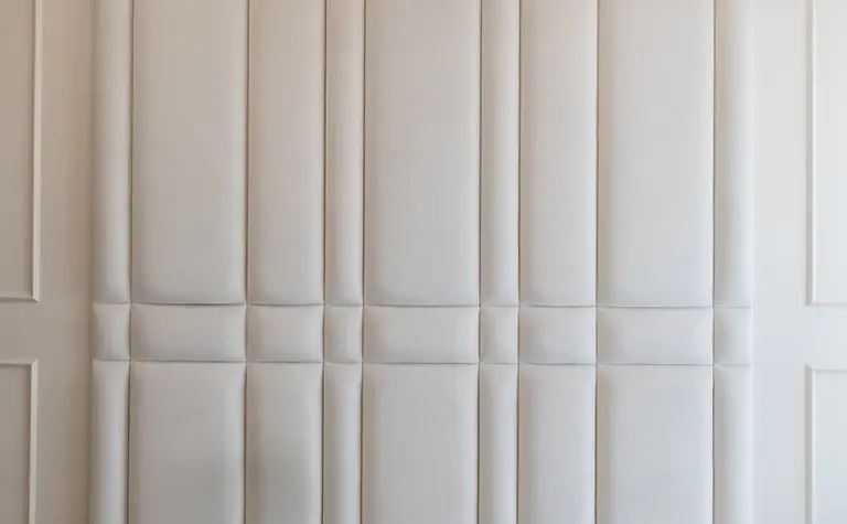 Wnętrze sypialni z beżowym zagłówkiem, szarymi poduszkami, styl art deco, nowoczesny, quiet luxury.