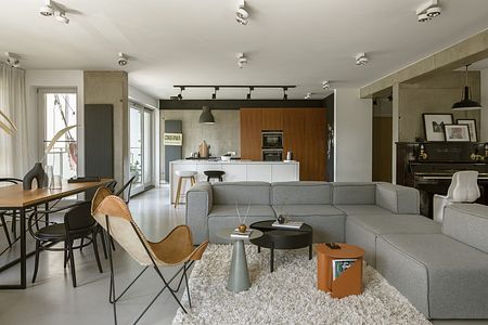 Wnętrze salonu w stylach boho, industrialnym i nowoczesnym z szarym narożnikiem.