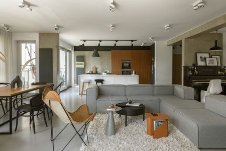 Wnętrze salonu w stylach boho, industrialnym i nowoczesnym z szarym narożnikiem.