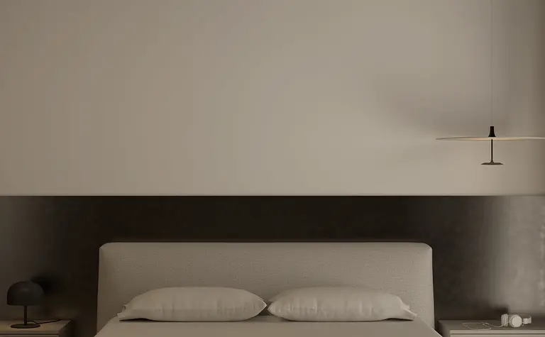 Minimalistyczna sypialnia z szarym łóżkiem i lampą.