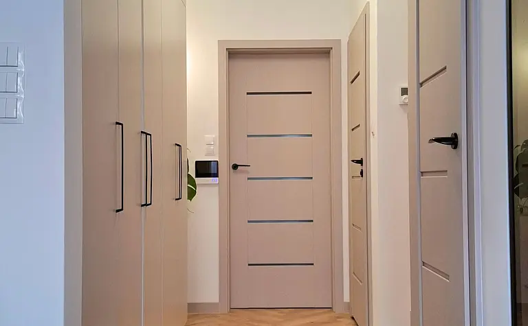 Stylowy przedpokój z jasnymi szafkami i podłogą w jodełkę, nowoczesny i skandynawski.