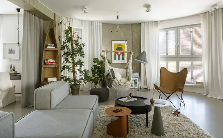 Wnętrze salonu w stylu boho i industrialnym z szarym narożnikiem oraz roślinami.