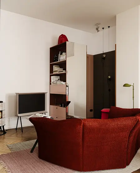 Eklektyczne wnętrze z czerwonym fotelem i telewizorem w minimalistycznym stylu.