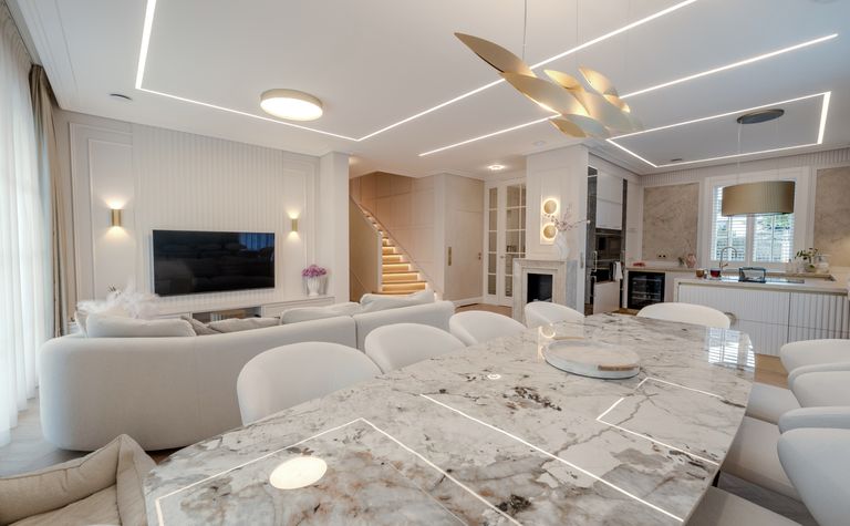 Wnętrze salonu z jasnymi meblami, eleganckim stołem, w stylu art deco, eklektycznym i współczesnym.