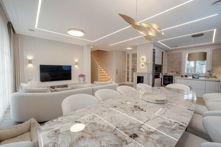 Wnętrze salonu z jasnymi meblami, eleganckim stołem, w stylu art deco, eklektycznym i współczesnym.