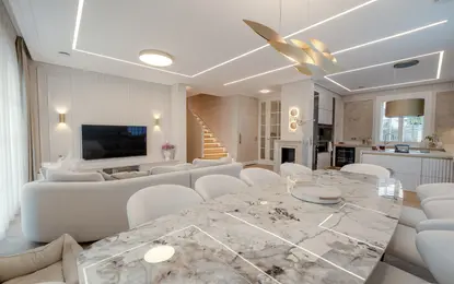 Wnętrze salonu z jasnymi meblami, eleganckim stołem, w stylu art deco, eklektycznym i współczesnym.