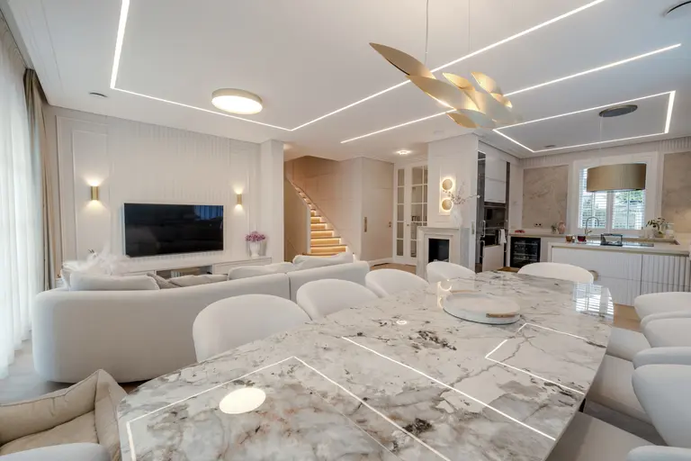Wnętrze salonu z jasnymi meblami, eleganckim stołem, w stylu art deco, eklektycznym i współczesnym.