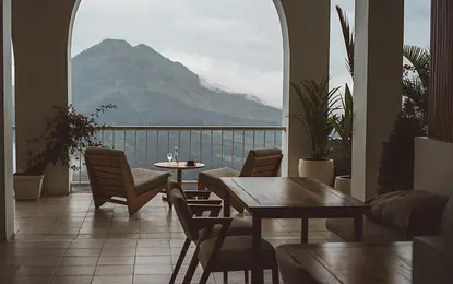 Wnętrze tarasu boho z drewnianymi meblami i roślinami, widok na góry.