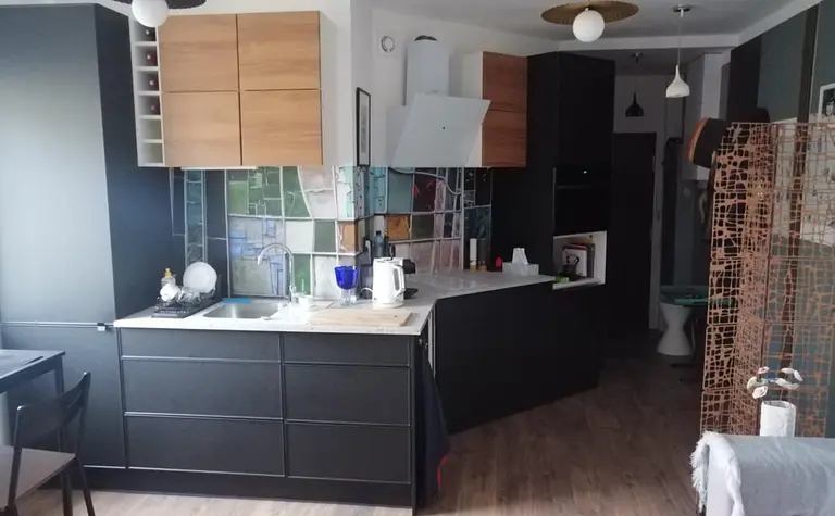 Kuchnia w stylu nowoczesnym z czarnymi meblami i drewnianymi detalami.